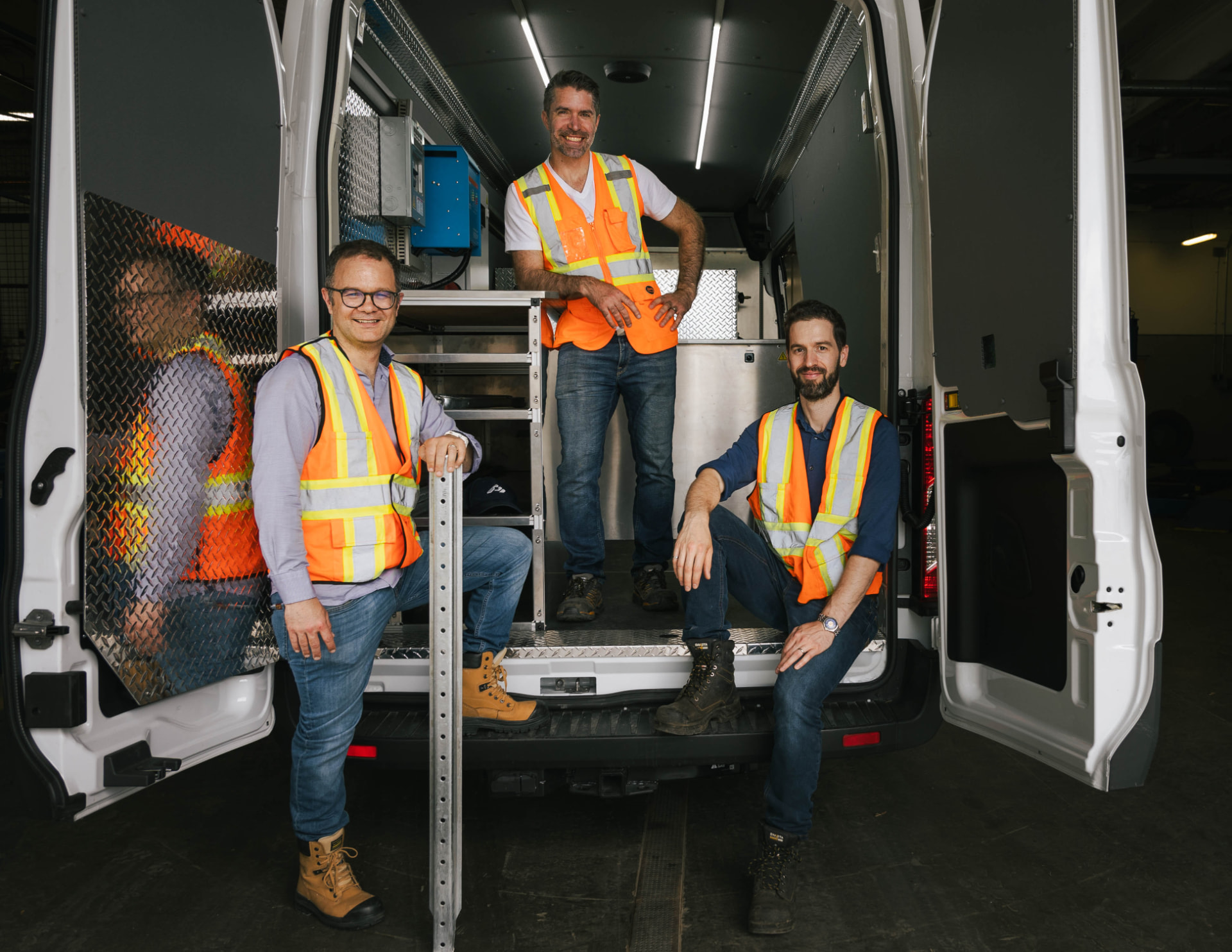 Three Gamotech team members at the back of an electrified service van